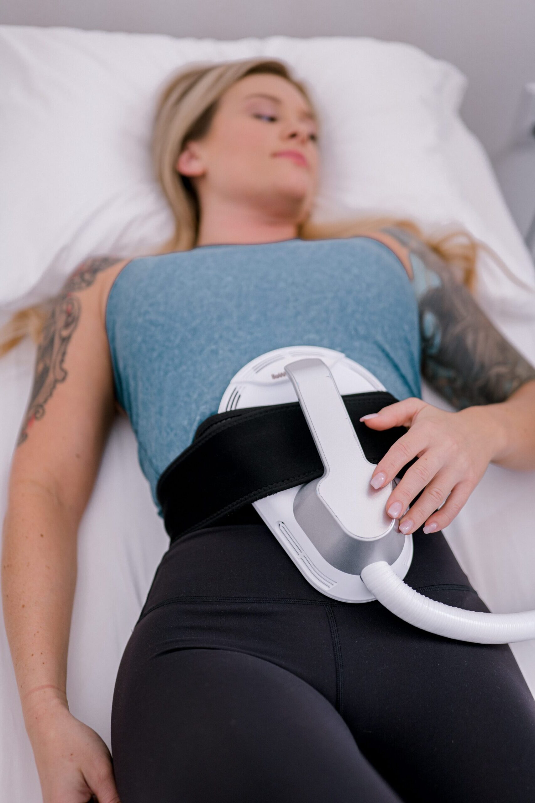 Relaxing woman receiving EMS Sculpt therapy on abdomen at ETHR LAB